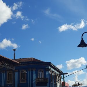 A vibrant blue building with ornate architectural details, including windows with decorative trim and a balcony, is partially visible in the foreground