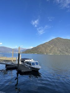 A boat at the Canobbio dock with mountains in the background in Italy.