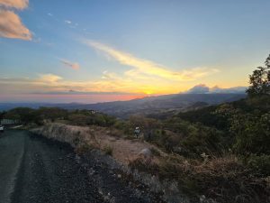 Wide mountain view at sunset with a gravel road in the foreground, showing depth and natural beauty.