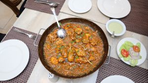 
A large serving dish filled with a flavorful chicken curry, garnished with fresh green herbs. 