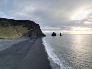 Black sand beach in Iceland featuring volcanic sand, ocean waves, and coastal landscape.