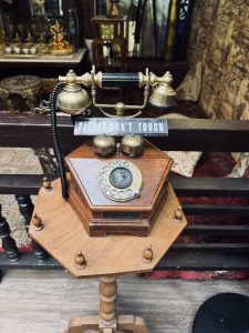 An antique telephone sits on an octagonal wooden pedestal. 