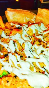 Close-up of shawarma with seasoned meat and a drizzle of white sauce.