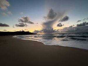A serene sunset beach with gentle waves on the shore in Sardinia Island, Italy.