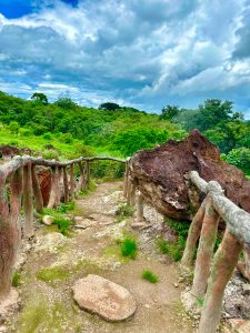 Natural trail with wooden railing and cloudy sky.