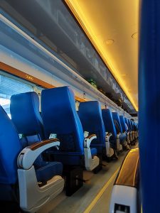 A view down the denter aisle of a train, filled with empty seats.