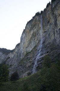 A small mountain waterfall flowing over rocks in a natural landscape.