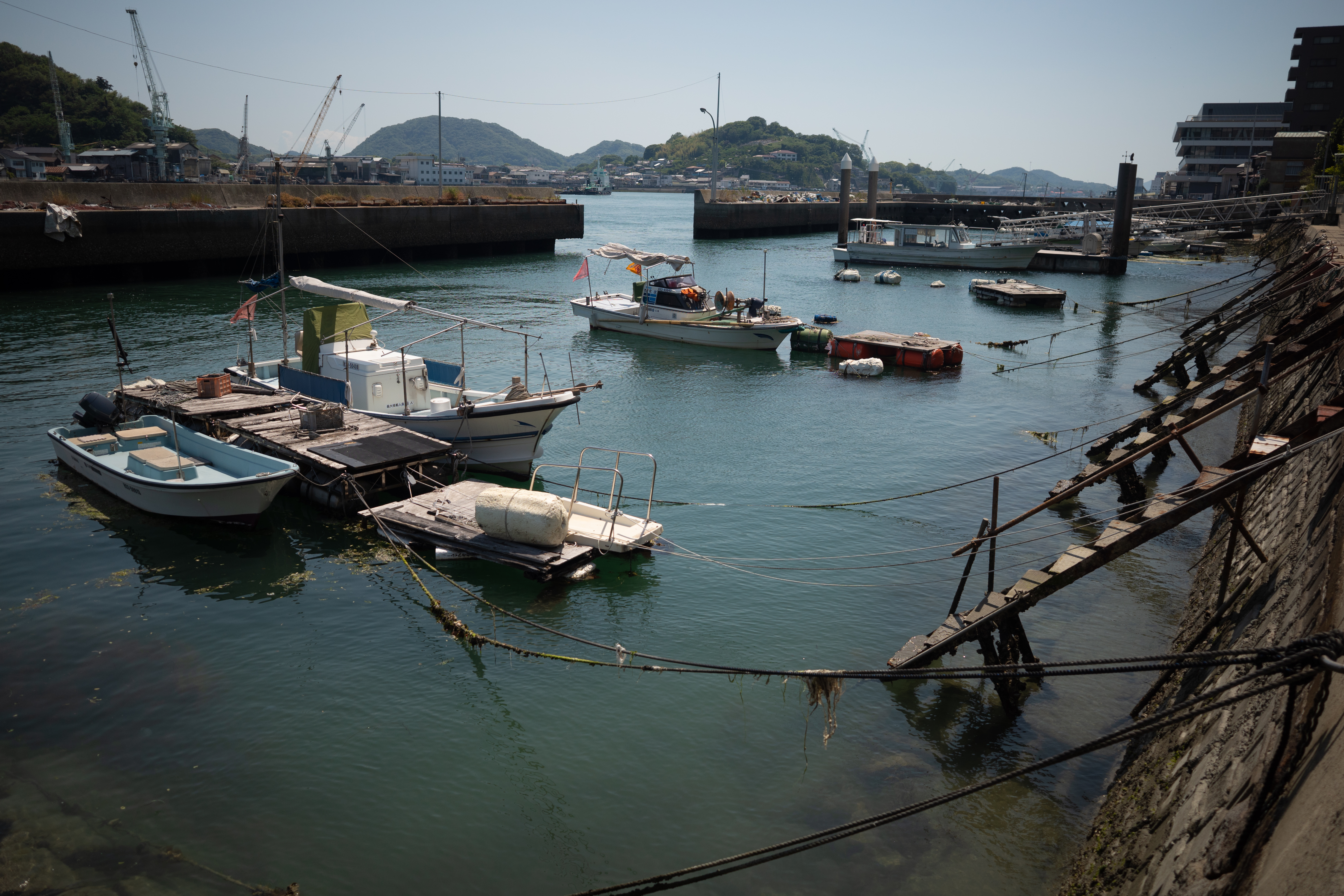 Small fishing boats moored in a calm harbor in Onomichi, Hiroshima, on a sunny day.