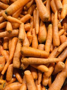 A pile of fresh, unwashed carrots with varying sizes and a vibrant orange hue. 