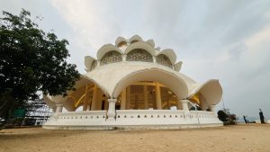 Lotus-shaped white building - known as Lotus Temple, with curved arches and stained glass windows in a peaceful outdoor setting.