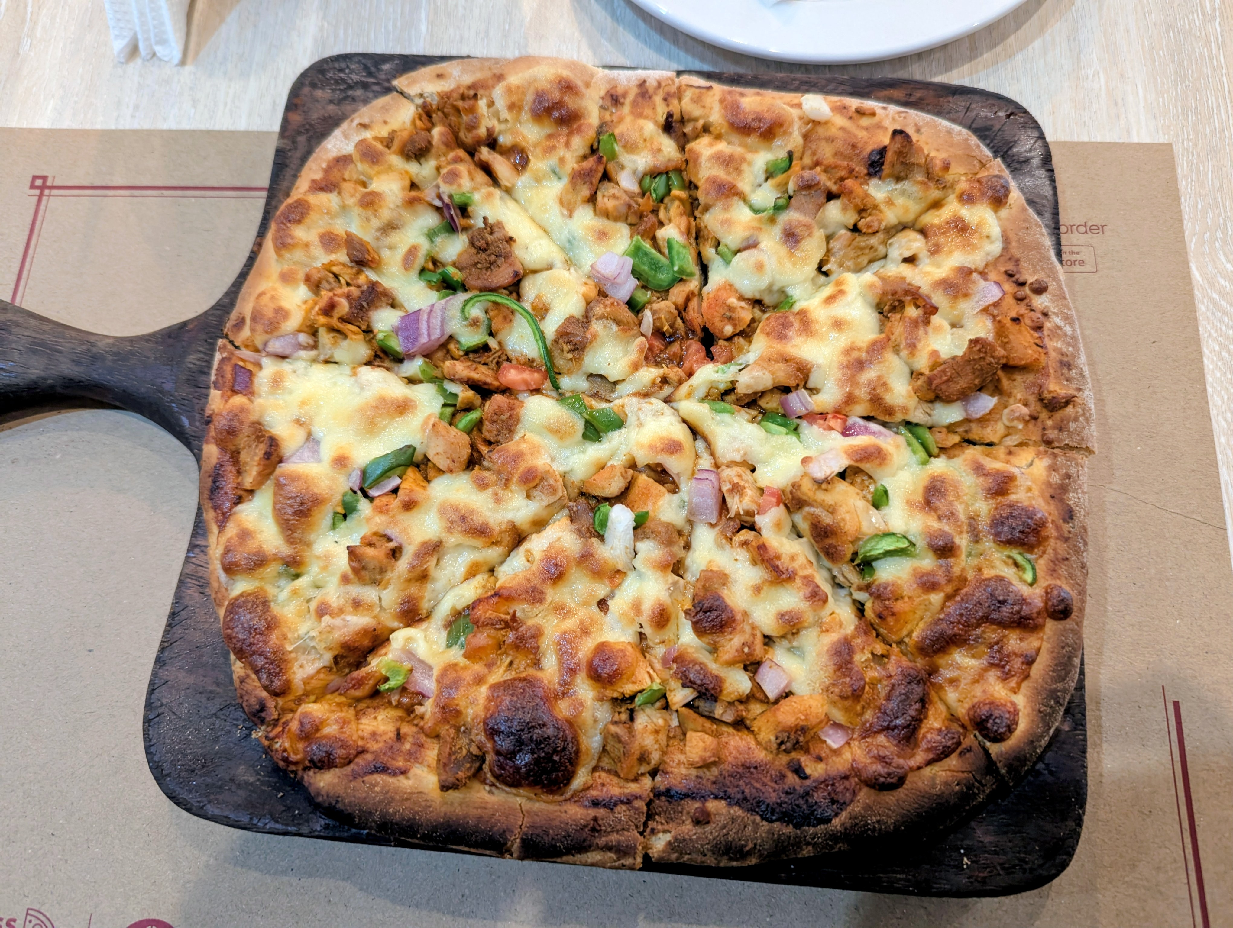 freshly baked, artisanal pizza served on a dark wooden paddle board.