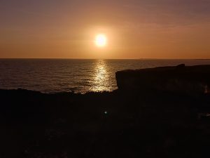 A golden sunset over the ocean, casting a glowing reflection on the water.
