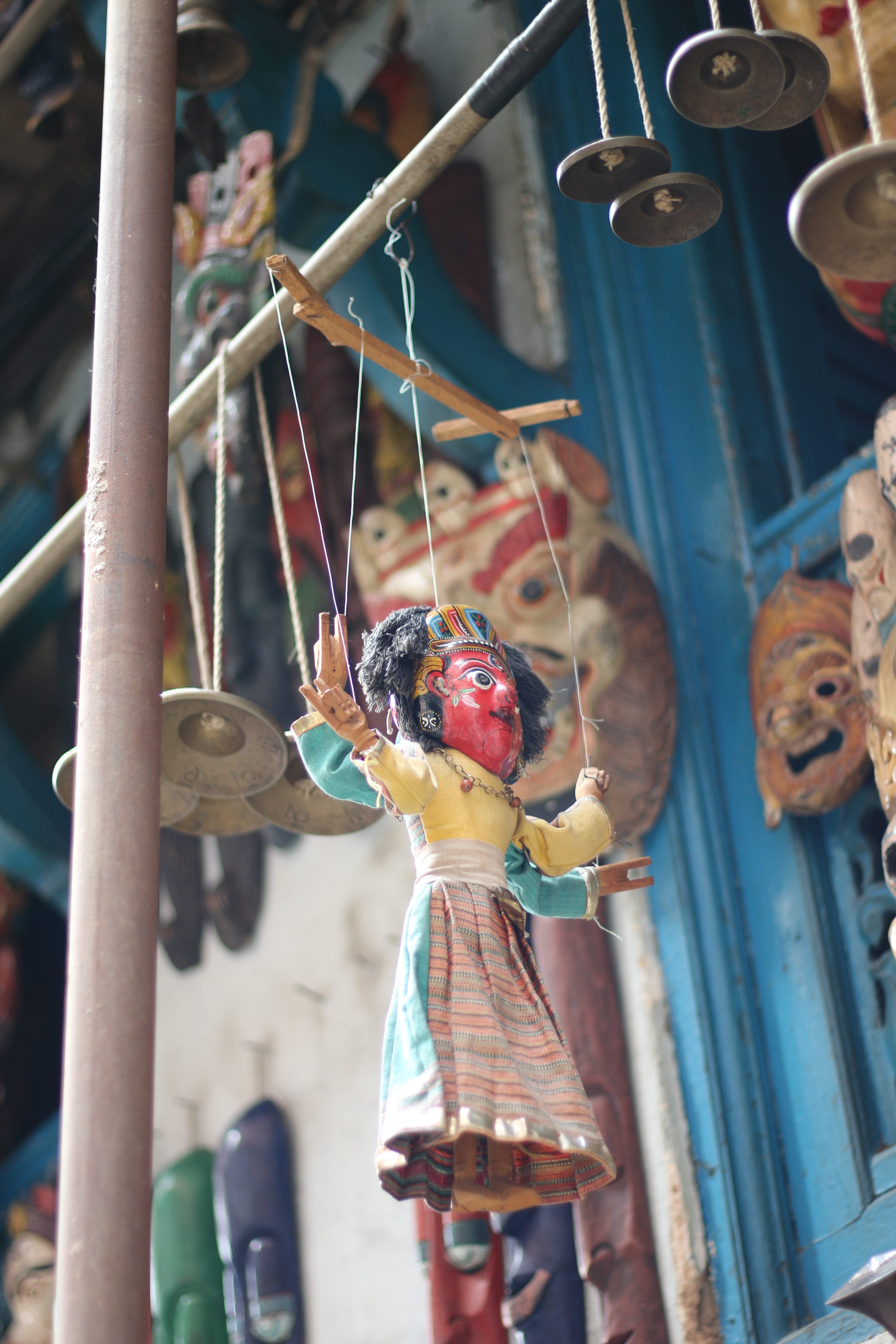 kathmandu
A colorful marionette with a red face and bright attire hangs among bronze cymbals against a backdrop of intricate masks, evoking a lively and cultural atmosphere.