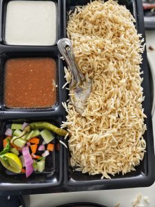 
A divided food tray containing a large portion of fluffy rice on one side. 