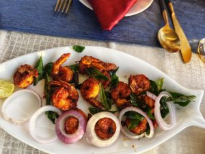 Prawns 

A beautifully presented dish of cooked Prawns garnished with fresh curry leaves and served with slices of red onion and a wedge of lime. 