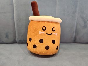 A cute bubble tea plush toy with a smiling face sits on a sofa, adding a soft, cheerful feel. Captured indoors in Kurla, Mumbai. 