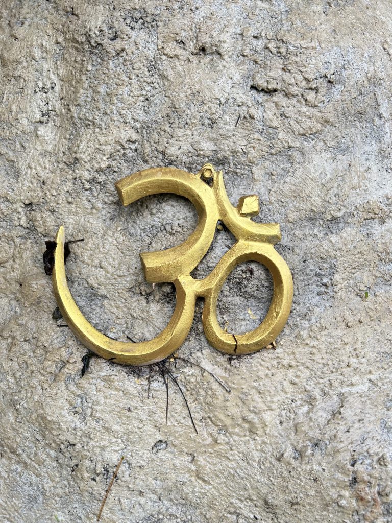 Golden Om symbol on textured stone, conveying a sense of spirituality and calm.