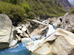 A mountain stream cascades over large rocks, with water splashing energetically. 