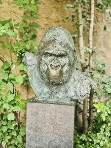 A detailed sculpture of “Matze,” the famous silverback gorilla of the Frankfurt Zoo (Germany), stands among green plants and trees, creating a calm atmosphere.