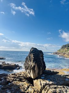 A view of a big rock in the edge of the beach
