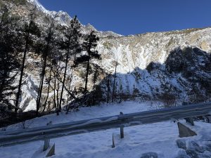 Snowy mountain landscape with a metal guardrail in the foreground.
