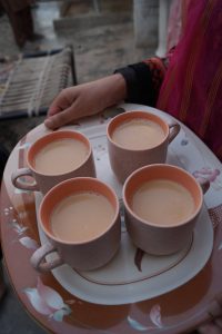 A person holding a tray filled with several cups of tea, ready to serve.