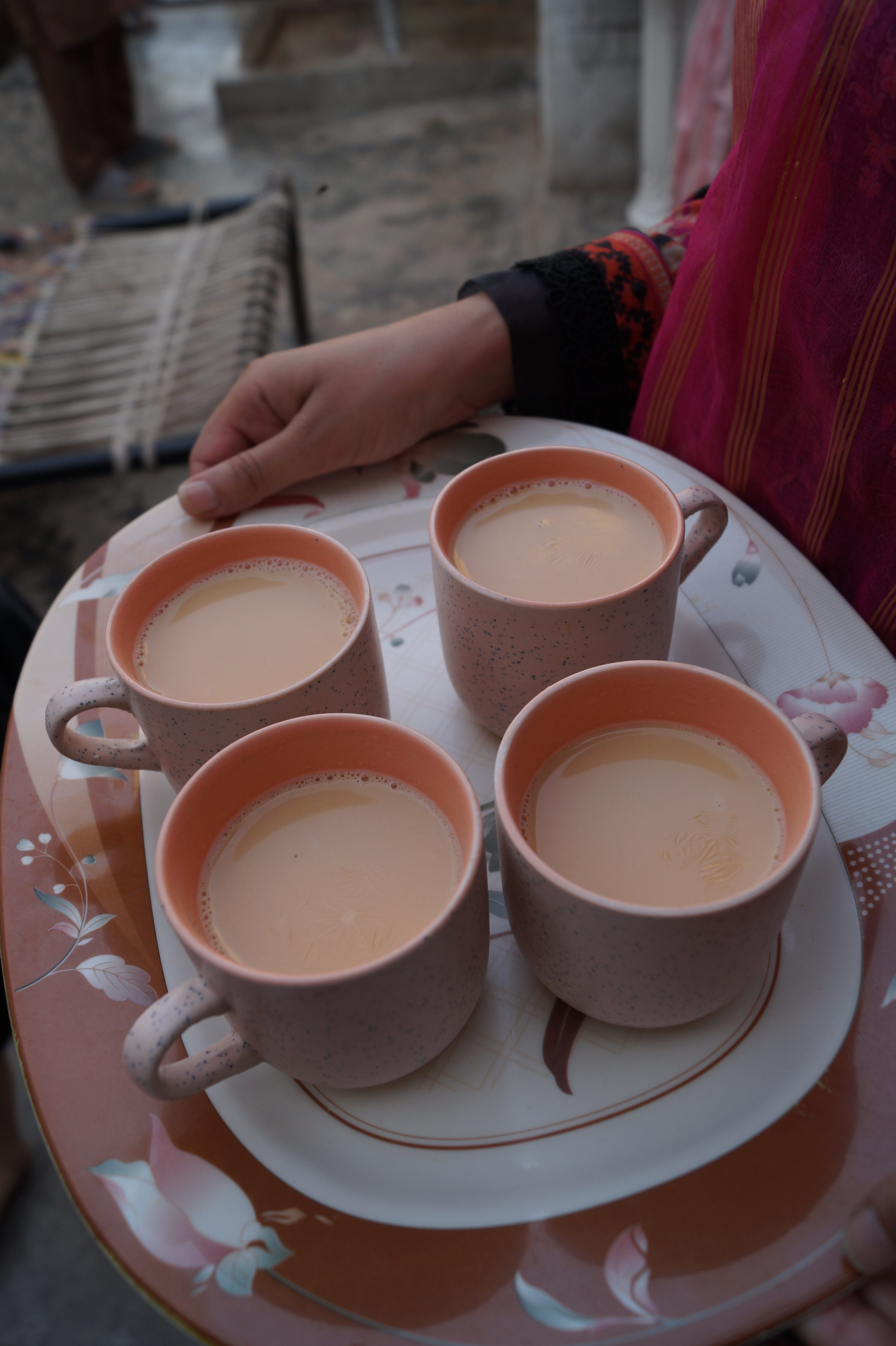 A person holding a tray filled with several cups of tea, ready to serve.