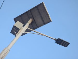 A modern solar-powered street light stands against the sky.