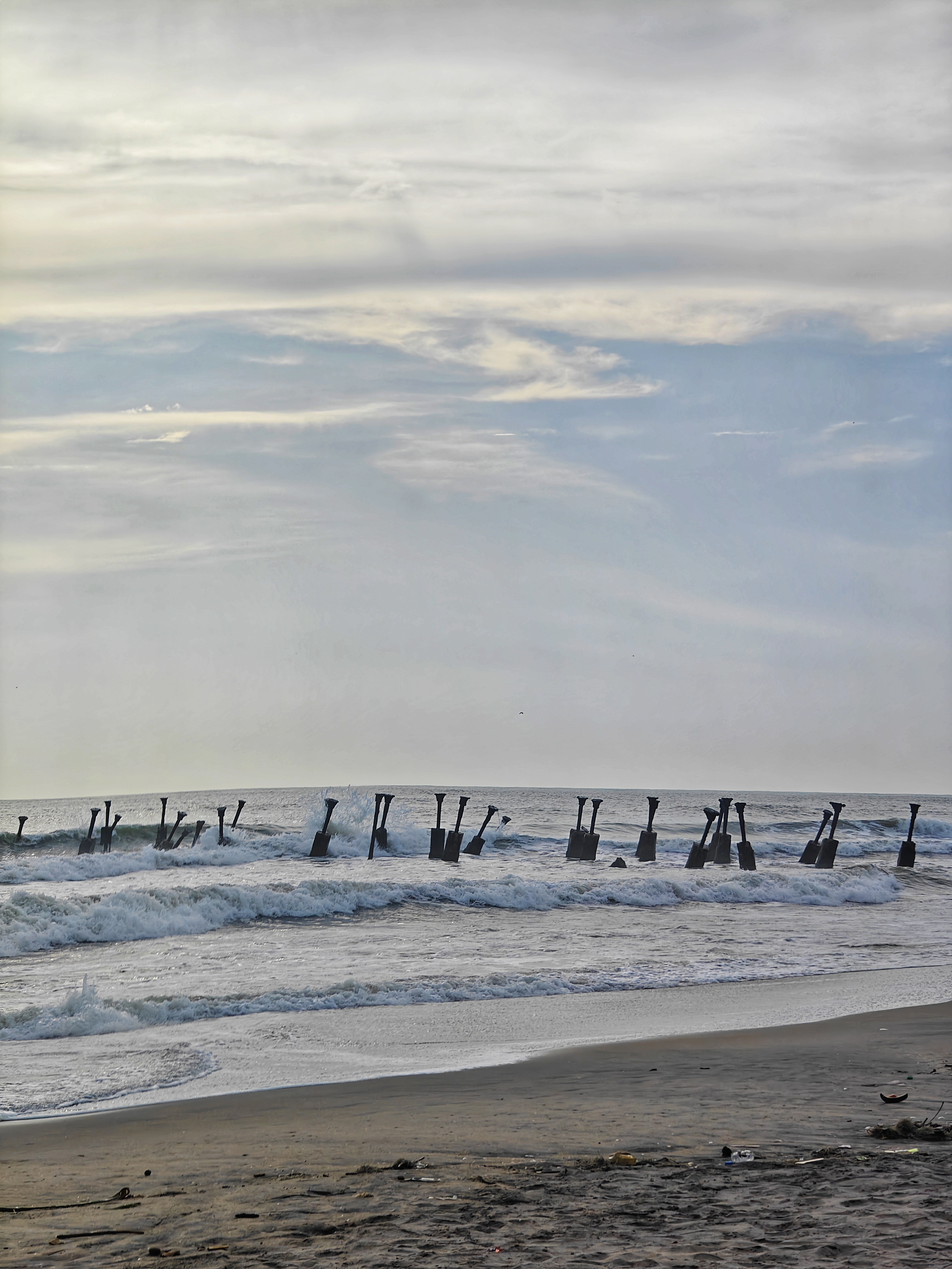 A serene beach scene featuring gentle waves lapping at the shore beneath a cloudy sky.
