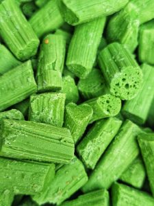 A close-up of small green cylindrical candy pieces stacked closely together.