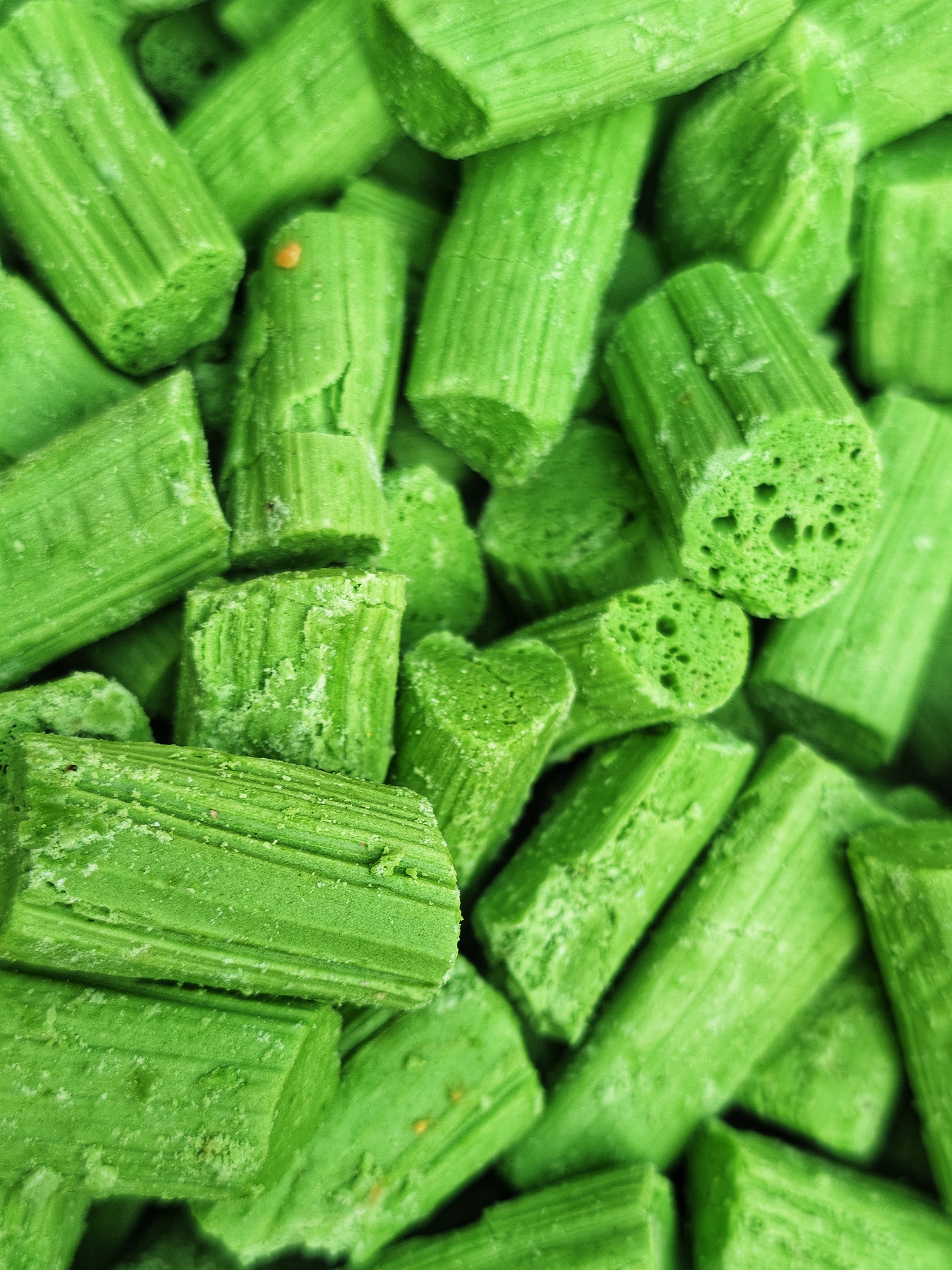 A close-up of small green cylindrical candy pieces stacked closely together.