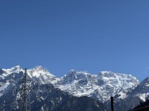 

Snow-capped mountains under a clear blue sky, with a metal electricity pylon in the foreground. 
