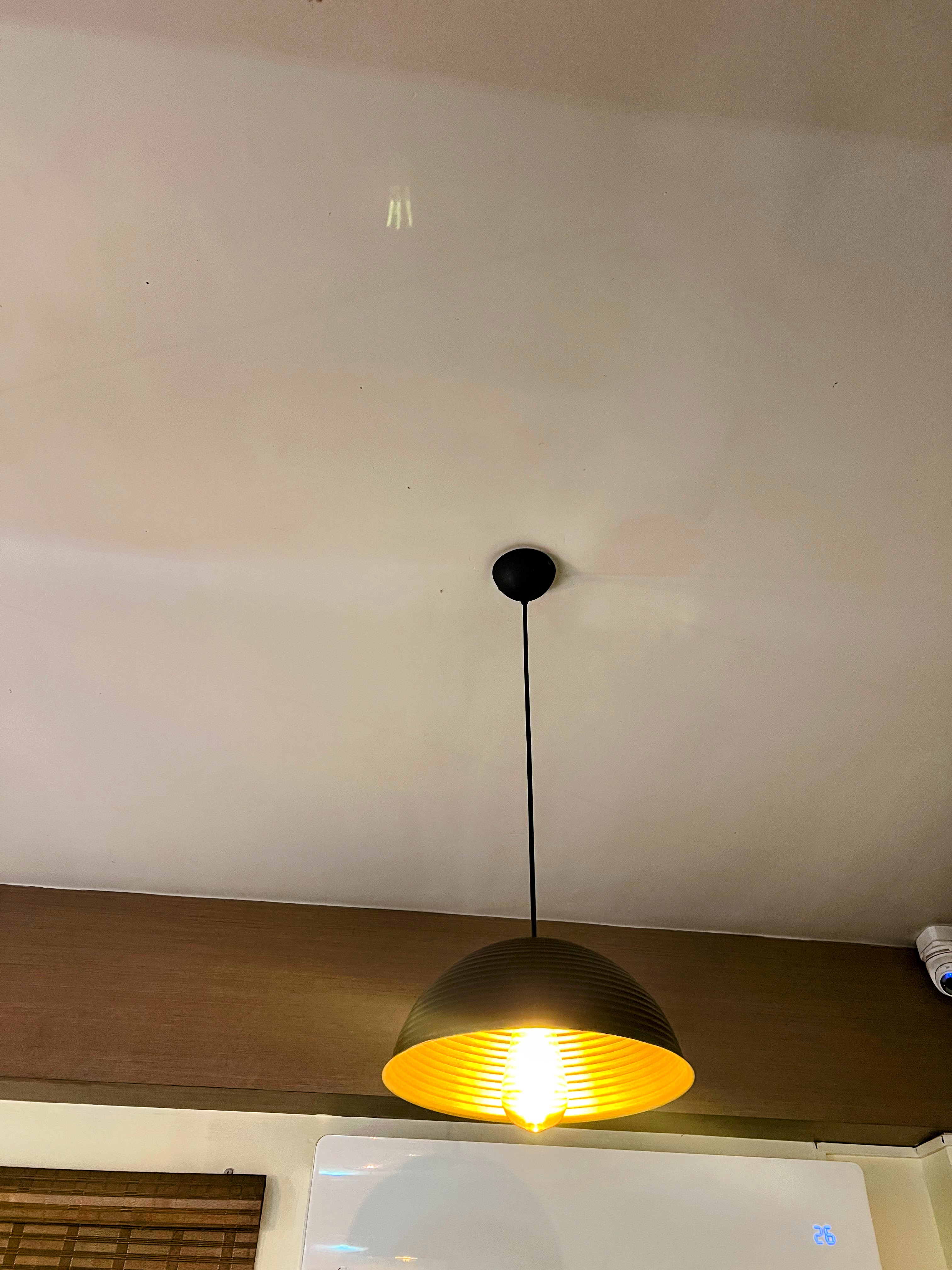 A modern black dome pendant light with a warm, glowing bulb hanging from a ceiling.
