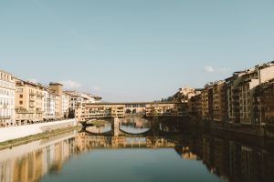 Straight on view of the Ponte Vecchio with a reflection in the water. 