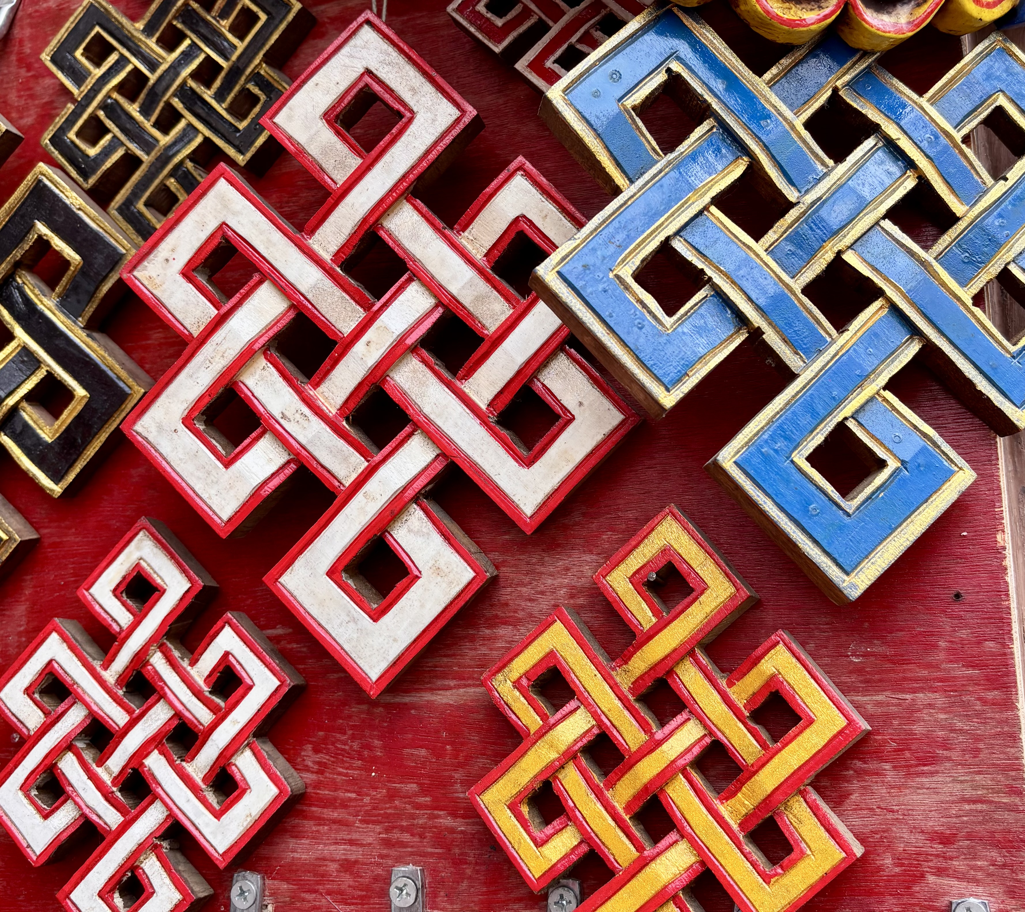 Colorful geometric endless knot patterns overlap on a red background.