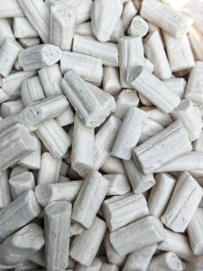 A close-up of small white cylindrical candy pieces with textured surfaces and varying heights.