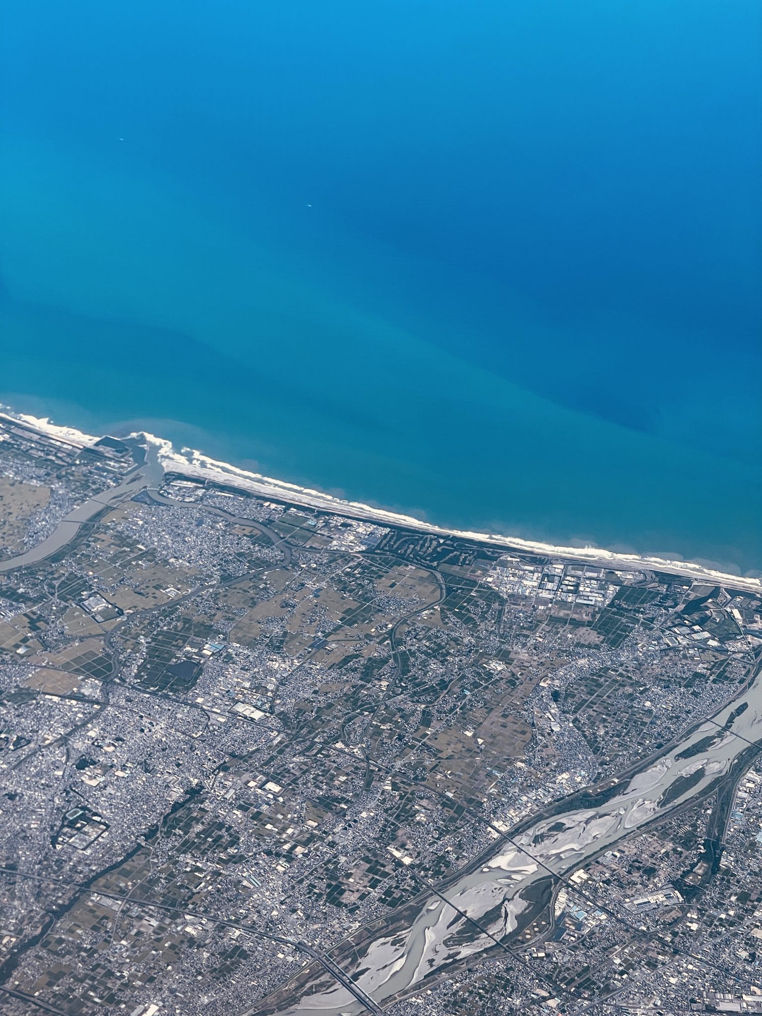 Aerial view of a coastal city and river delta running into the sea — photograph by Sakin Shrestha, public domain via Openverse (CC0)