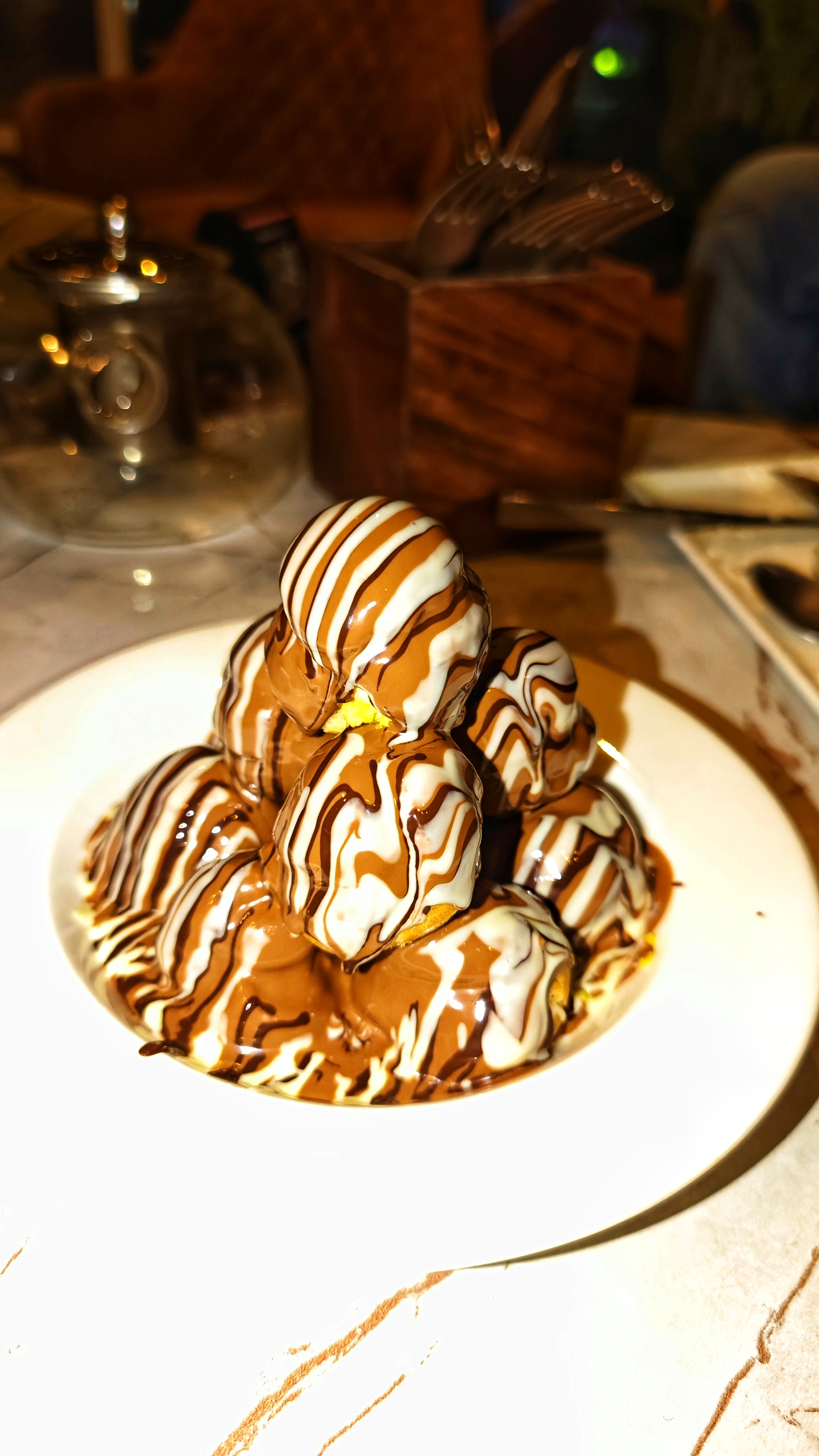 A stack of ice cream scoops drizzled with chocolate and cream on a white plate.
