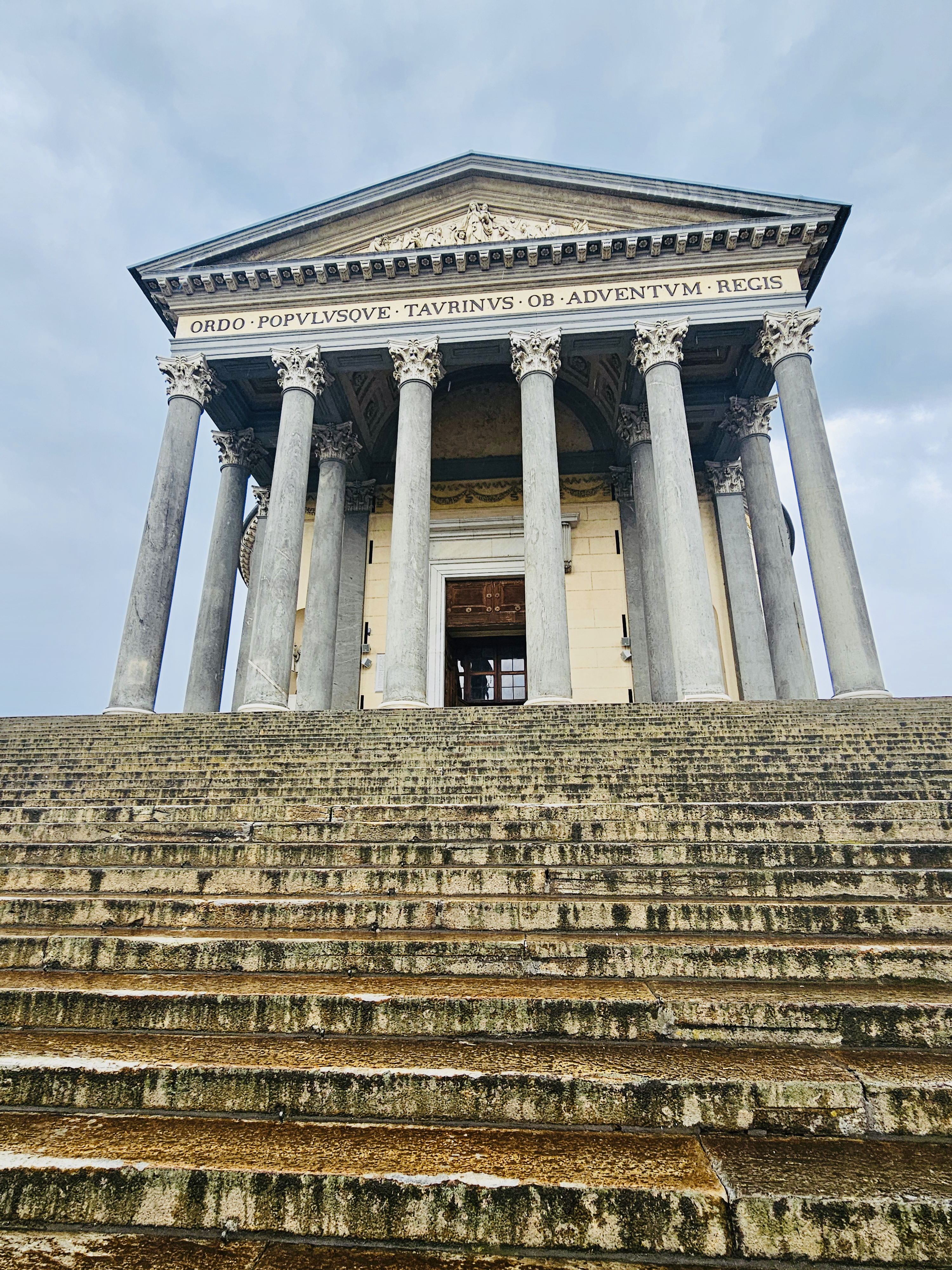 A majestic neoclassical church (Chiesa della Gran Madre di Dio) with tall pillars and long stone steps creates a powerful and dramatic scene under dark clouds in Turin (Torino), Italy.