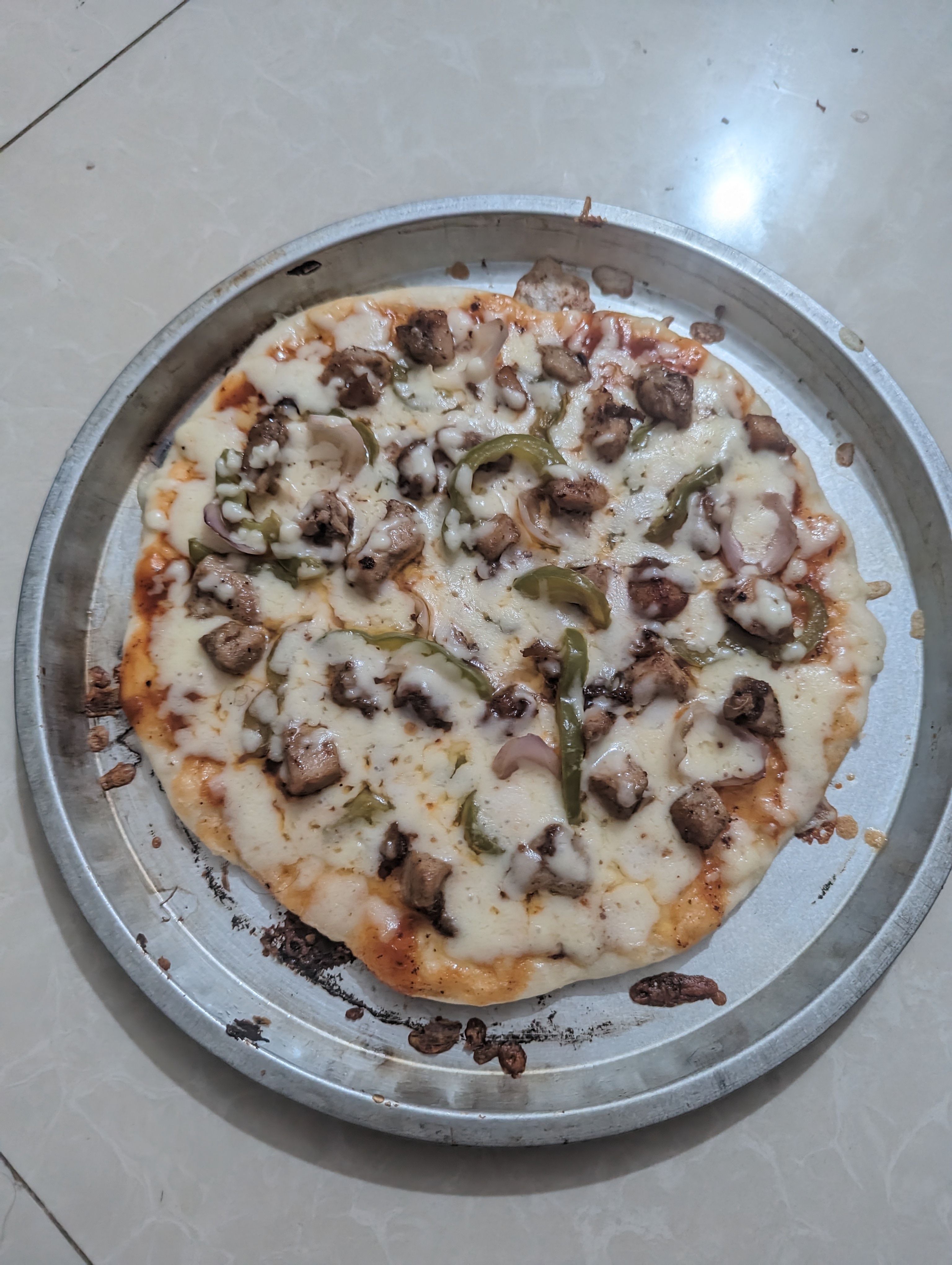 A homemade pizza on a tray with melted cheese, mushrooms, onions, and green peppers, looking warm and tasty.
