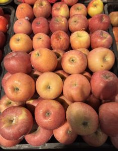 A pile of fresh, shiny apples with a warm red and yellow hue fills the frame. 
