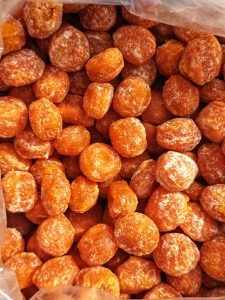 A close-up of small round orange honey candies lightly dusted with sugar.