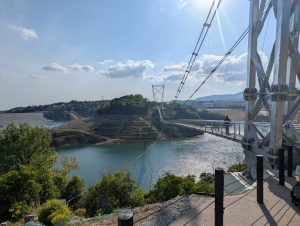 A panoramic view of GRAVITATE OSAKA featuring the 420-meter-long GODA BRIDGE, Japan’s longest pedestrian suspension bridge over Aigawa Dam.