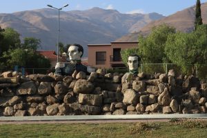 Two historical sculptures among large rocks with mountains in the background, blending art, nature, and architecture in a peaceful majestic setting.
