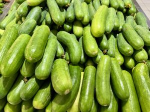A pile of fresh, green cucumbers displayed in a market setting. 