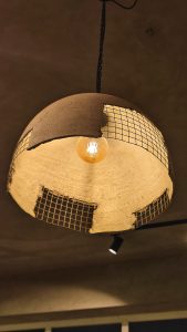 
A pendant light fixture with a round, bowl-like shape made of a textured, light-colored material