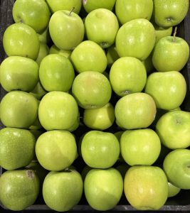 A neat grid of vibrant green apples stacked in a market display.