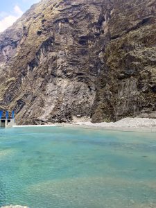 A tranquil lake with turquoise water, bordered by steep rugged cliffs.