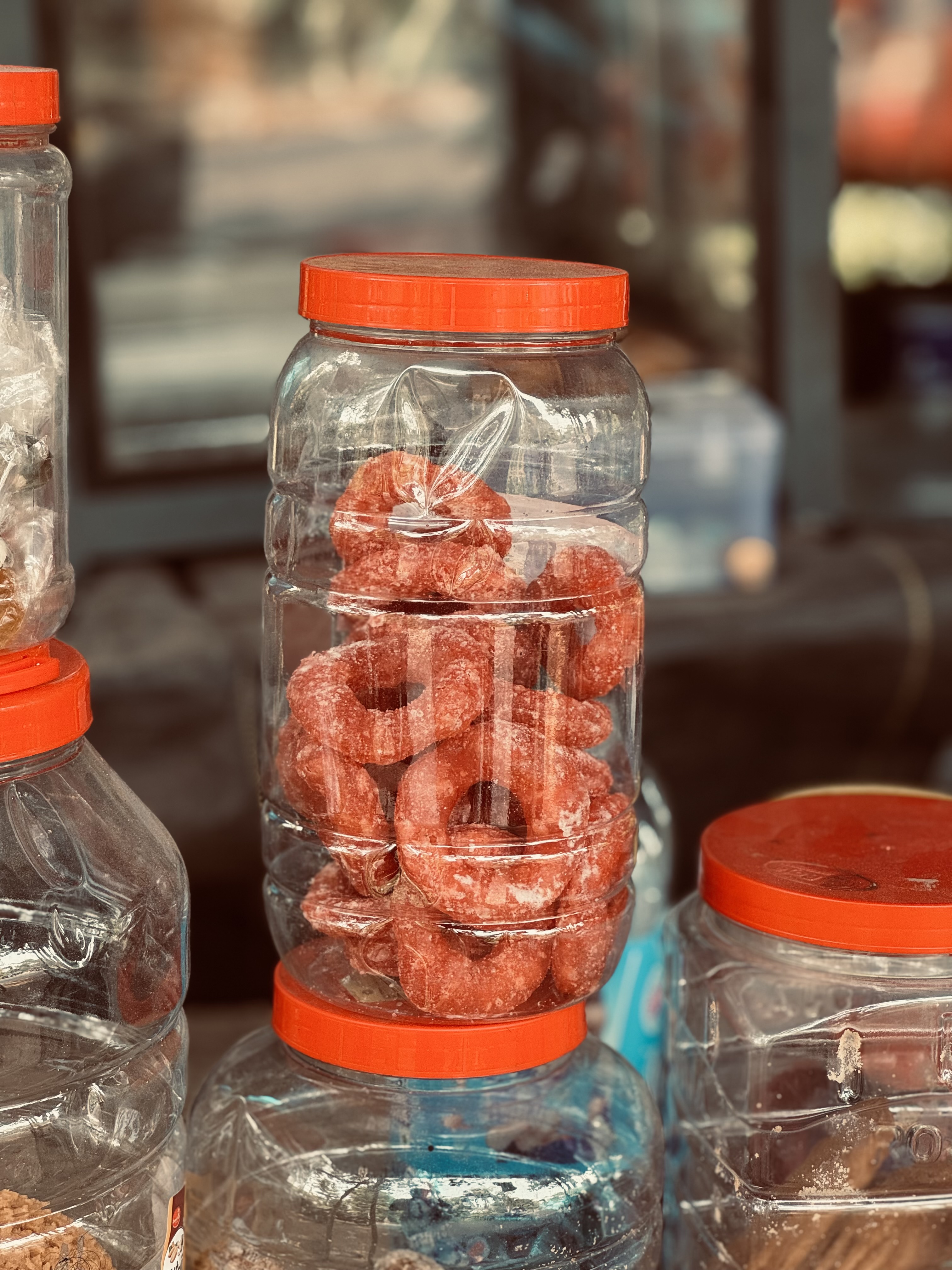 Transparent jars of orange honey candy stacked on a surface.