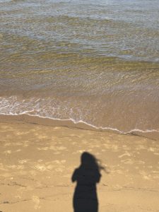 An image of a shadow of the girl standing on the edge of the beach.
